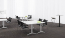 meeting room with white modular tables and black plastic chairs