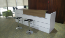office reception area with white reception table and two bar stools in black leather